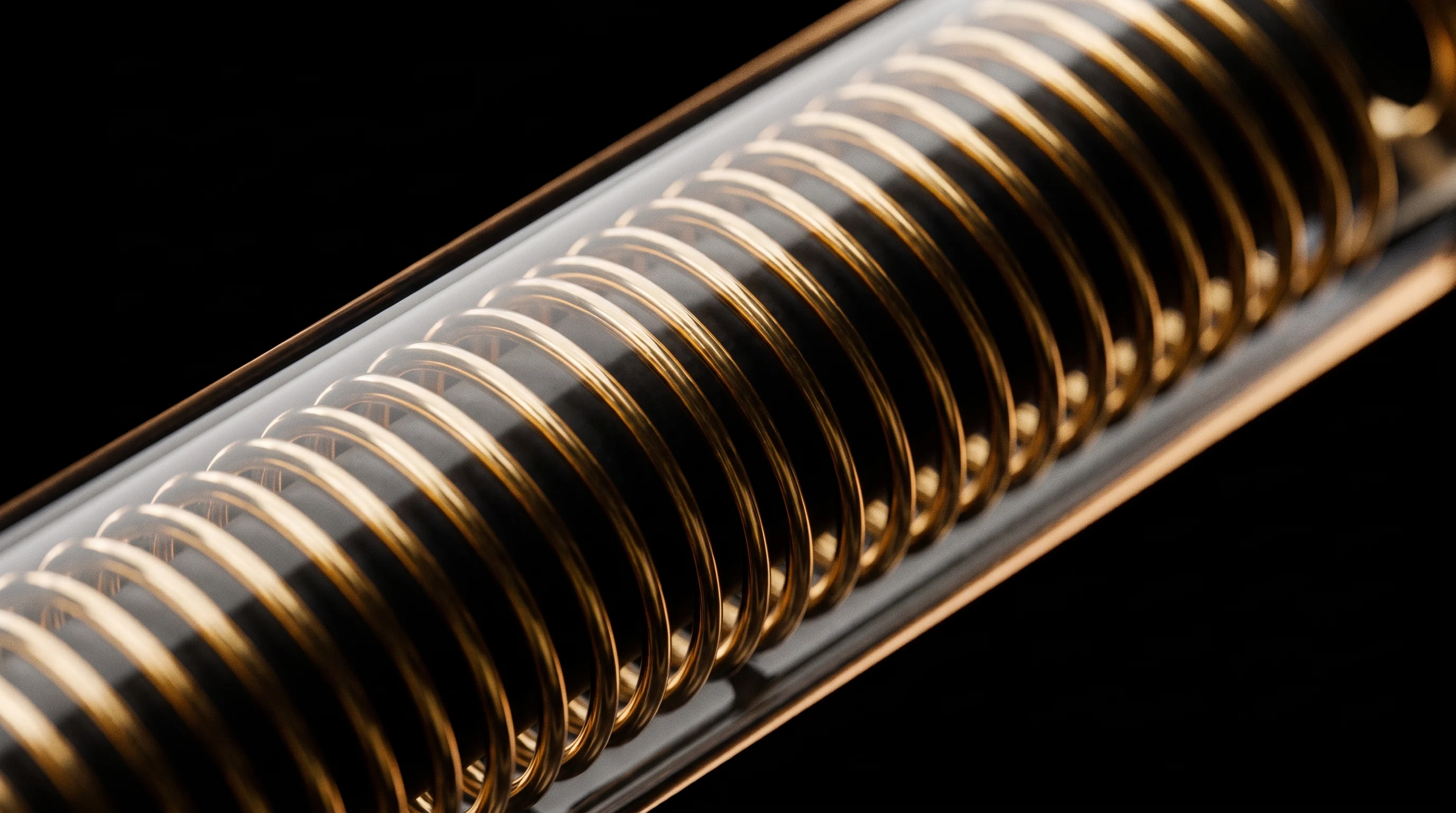Macro of the induction coil: fine copper-gold wire wound on black ferrite, seen through curved glass.